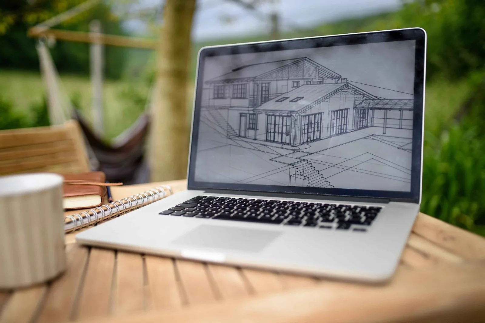 Laptop with blueprints on a desk showing 3D home design software