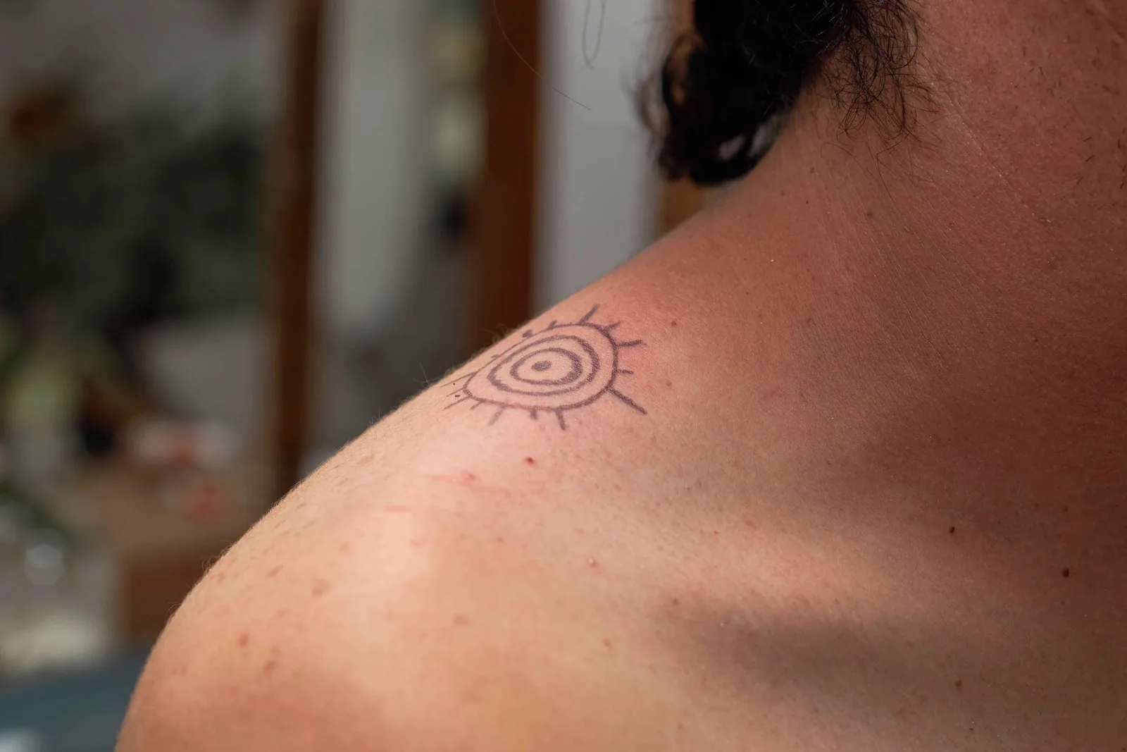 Hand-poked name tattoo on shoulder near neck