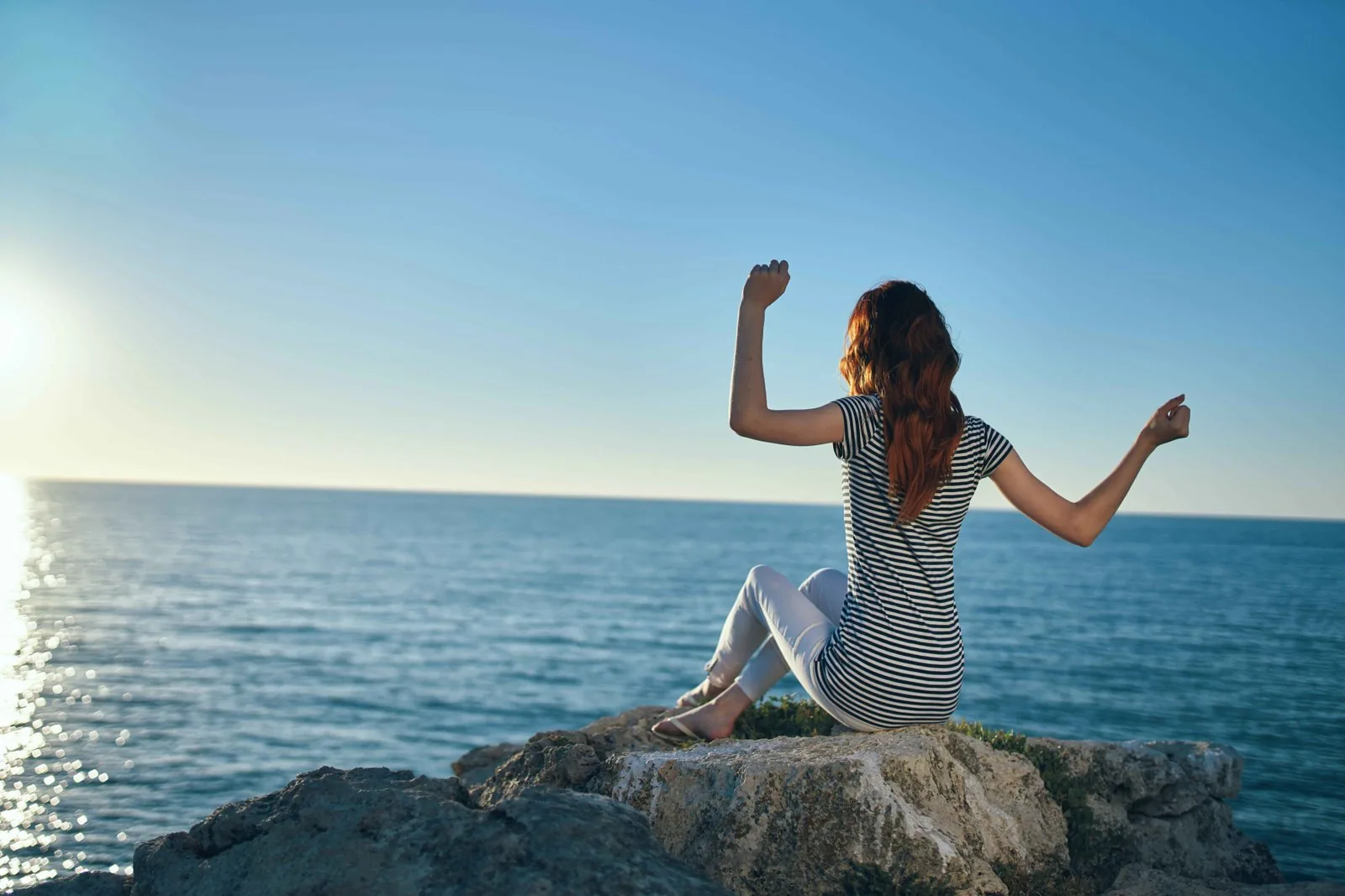 Woman standing in the mountains near the sea, embracing her journey forward